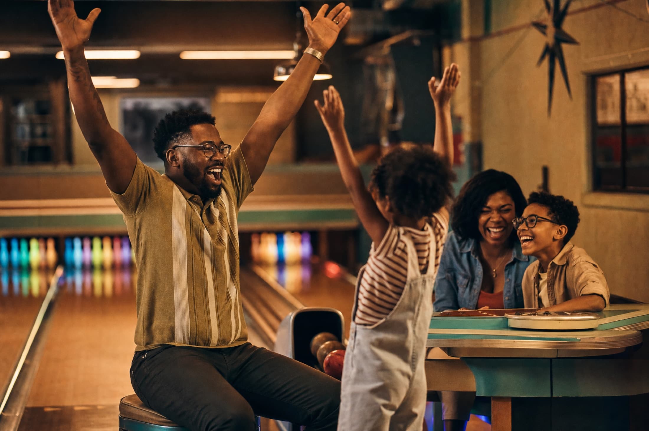A kid celebrating a strike while the whole family jumps up cheering behind them